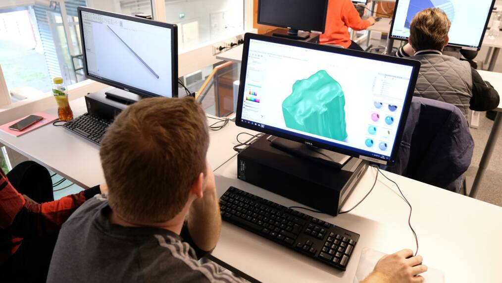 Ihmisiä tietokoneluokassa, tietkoneen ruudulla näkyy 3D-mallinnusohjelmalla työskentelyä.