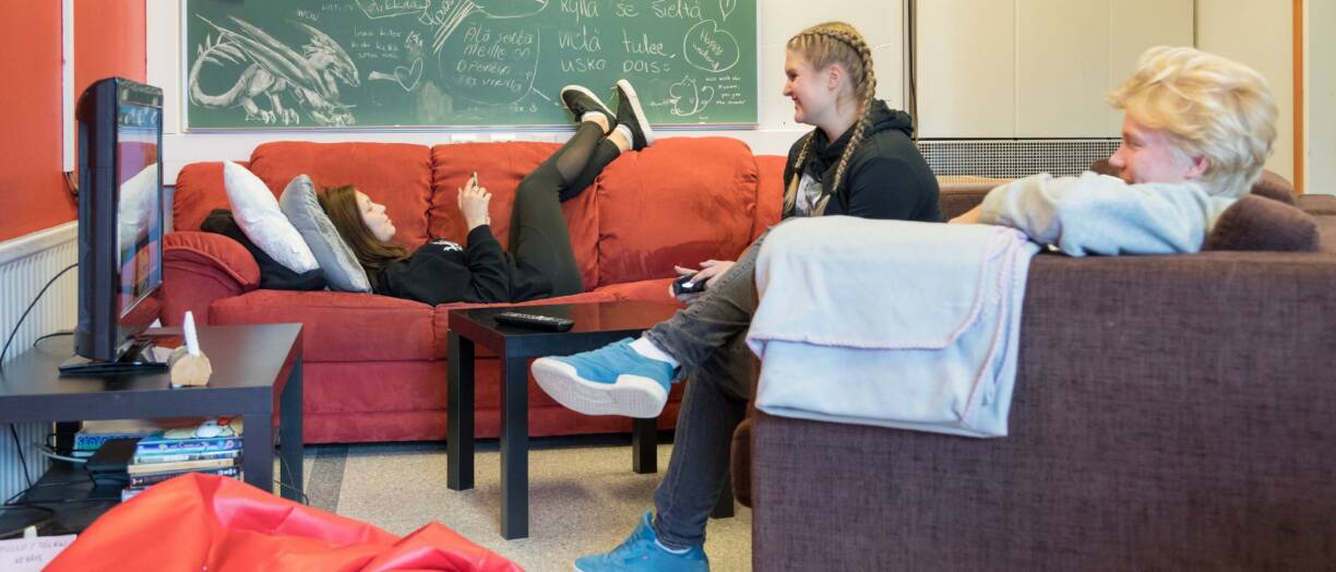 Kolme opiskelijaa löhöilemässä taukotilan sohvilla iloisina.