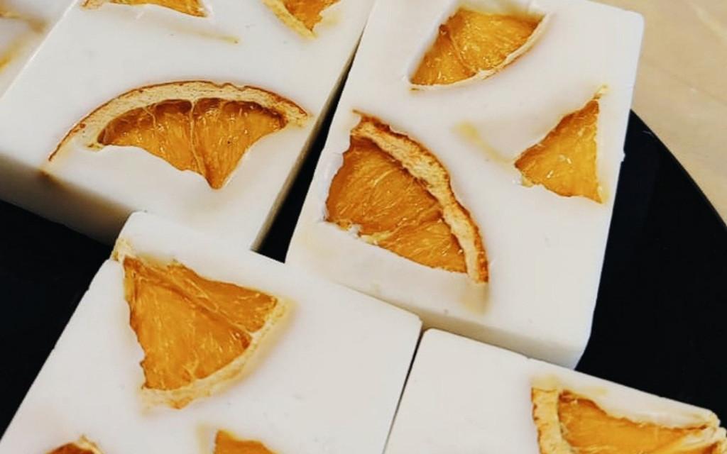 Valkoisia käsintehtyjä saippuoita, joissa koristeena kuivattuja appelsiin paloja.