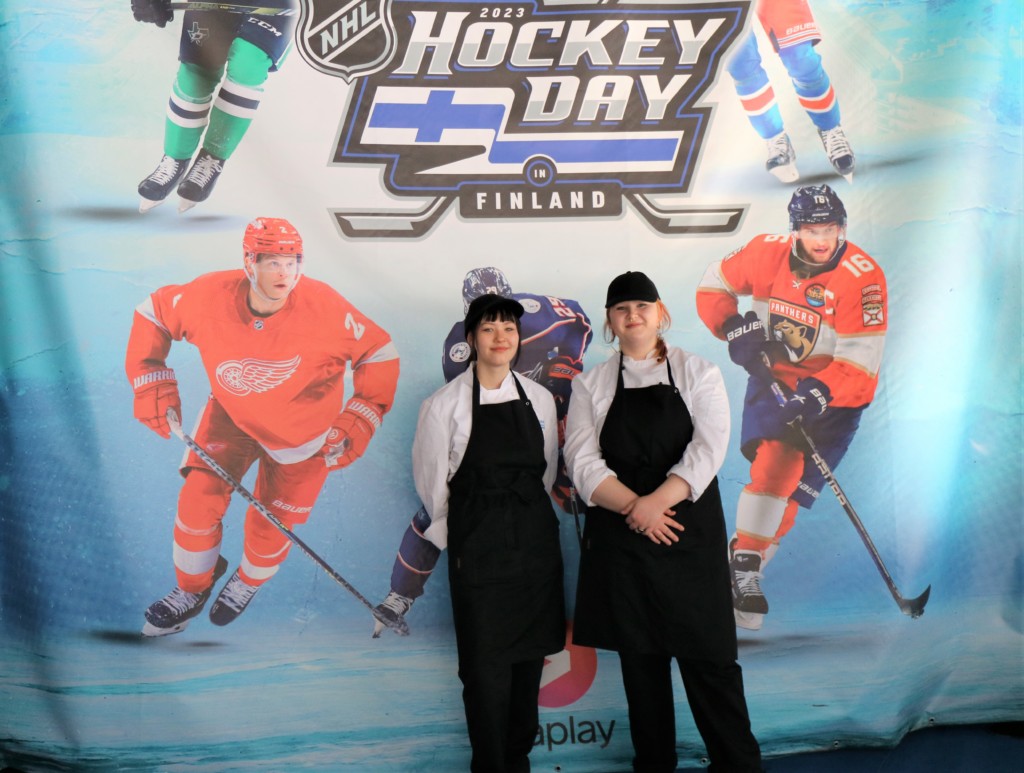 Kuvassa kaksi opiskelijaa Hockey Day-teemaisen julisteen edessä.