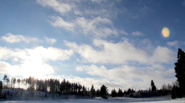 Talvinen maisema, valkoisia pilviä sinisellä taivaalla.
