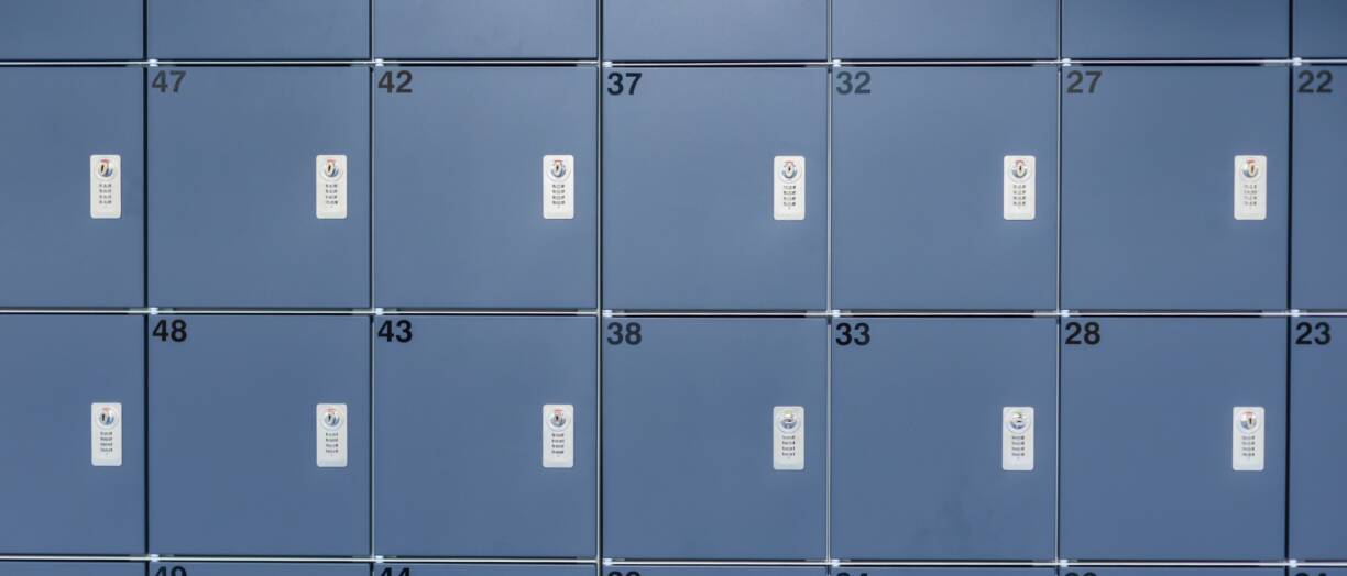 kuvassa siniharmaat koulukaapit. Kaapinovissa numerointi sekä lukko.