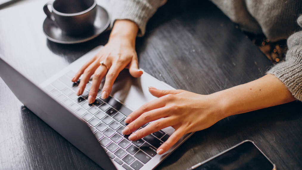 Naisen kädet kirjoittaa tietokoneella