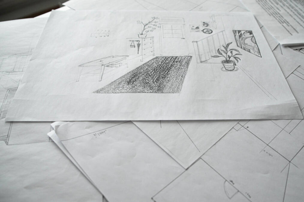 Pöydälle levitettyjä mustavalkoisia piirustuksia, joissa näkyy sisustussuunnitelmia.