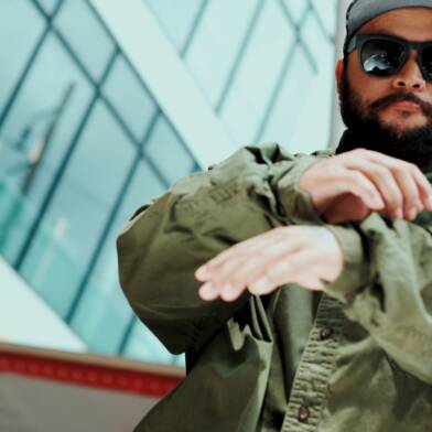 Aasialainen hipsteri katselee kameraa ja tanssii pilvenpiirtäjä taustallaan