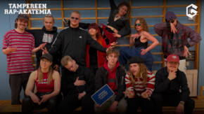 Kuvassa joukko nuoria henkilöitä. Taustalla puolapuut ja etummaisella henkilöllä kädessään kyltti, jossa lukee "Tampereen rap-akatemia class of 25".