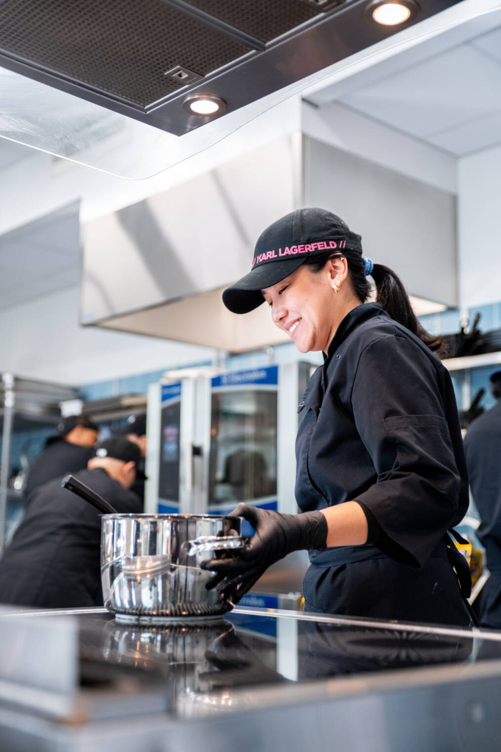 Opiskelija hymyilee työskennellessään kattilan äärellä ravintola- ja cateringalan opetuskeittiössä.