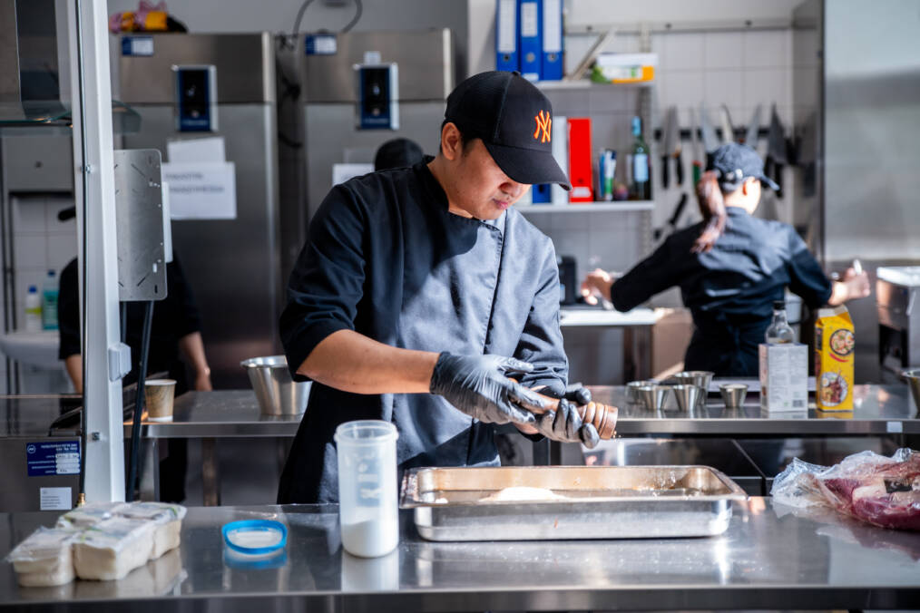 Ravintola- ja cateringalan opiskelija maustaa ruokaa opetuskeittiössä.