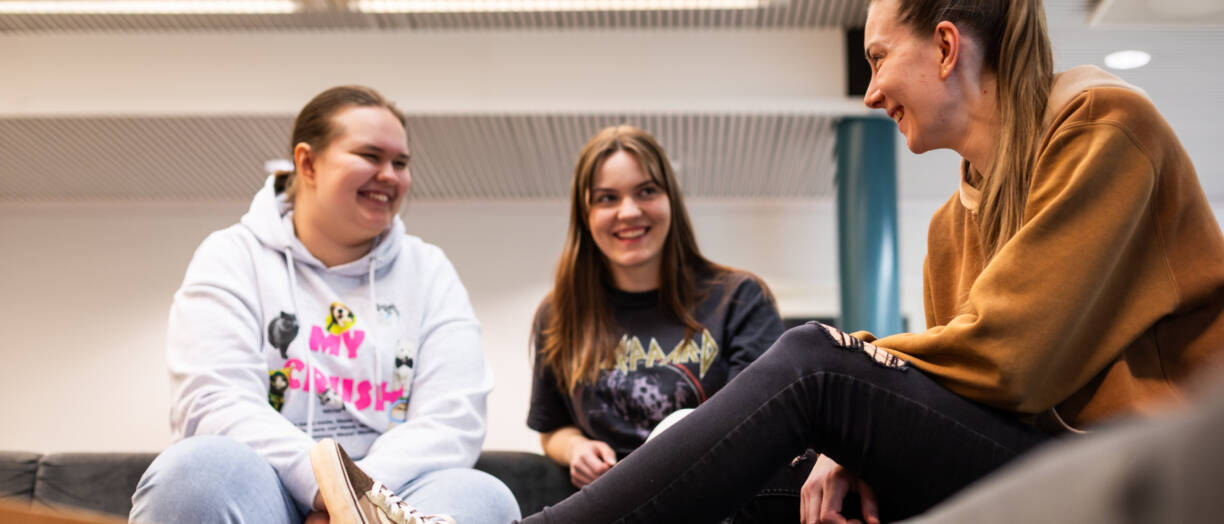 Kuvassa kolme henkilöä istuu rennosti sohvalla