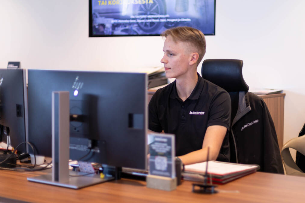 Nuori henkilö työskentelee tietokoneella AutoCenterin työnjohtajan työpisteellä.