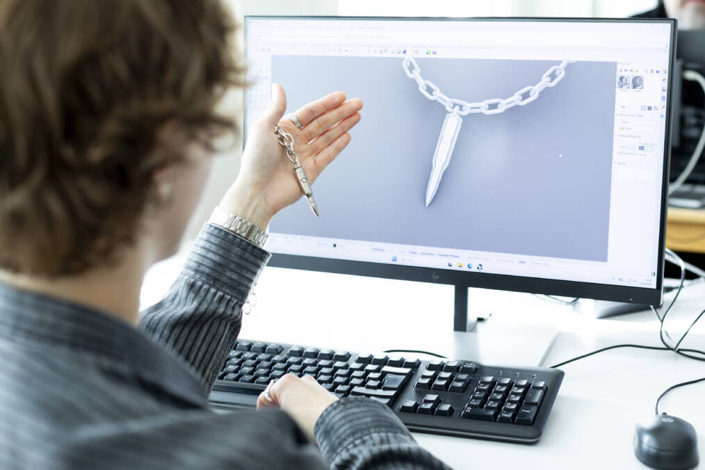Jalometallialan opiskelija esittelee tietokoneella korusta tehtyä 3D-mallia.